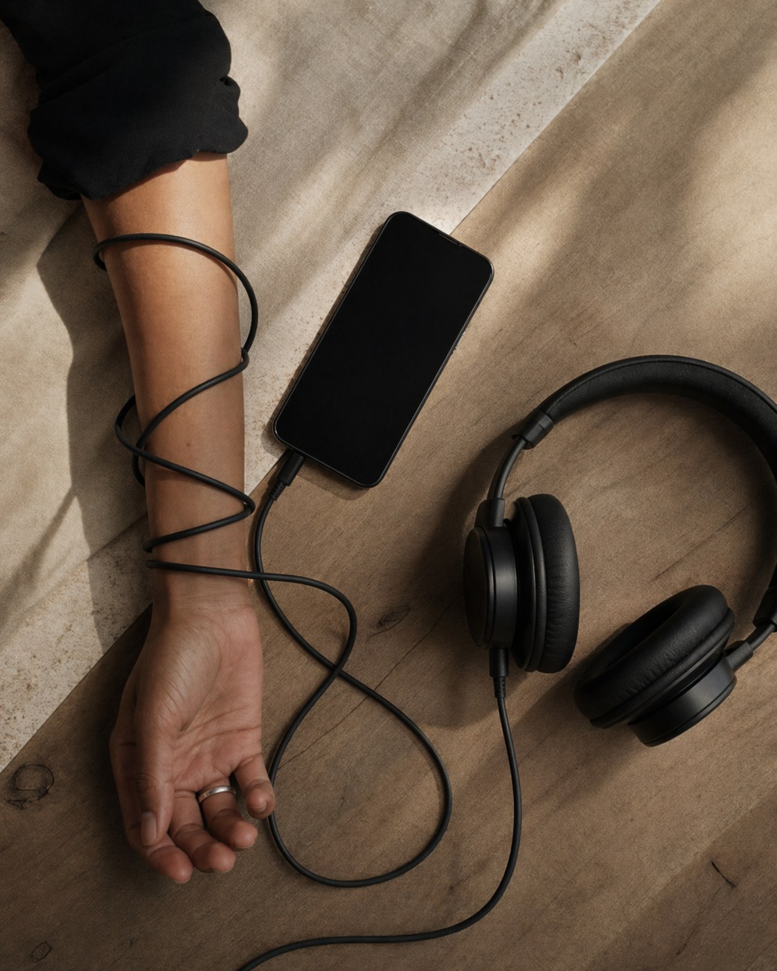Phone, cable, arm and headphones arranged as a quiet listening scene